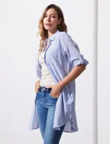 Camisola larga de algodón color blanco, marca Dash. Tiene cuello con solapa, abertura central con botones, bolsillo aplicado en el pecho, mangas regulables con presilla y botón, y bolsillos laterales en la costura.