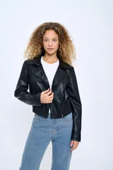 Campera corta de cuero sintético negro, estilo motoquero, con cuello clásico, cierre asimétrico con cremallera, bolsillos laterales con cremallera y puños con cremallera.