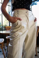 Pantalón cargo de cuerina color beige, tiro alto, corte holgado y bolsillos laterales.