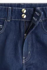 Short de jean azul oscuro, tiro alto, con cierre y doble botón metálico dorado. Presenta corte holgado y costuras visibles en hilo contrastante claro.