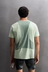 Camiseta deportiva verde claro confeccionada en tejido técnico, ligero y elástico en cuatro direcciones. Tiene cuello redondo, manga corta, zonas con estructura perforada y logo estampado.