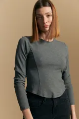 Remera de manga larga color gris oscuro, de tejido acanalado y corte ajustado al cuerpo, con costura diagonal decorativa en el frente.