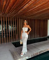 Vestido tejido strapless color blanco, con detalles calados y falda larga con flecos. Incluye short.