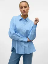 Camisa celeste a rayas blancas, holgada con cuello clásico, mangas largas y cierre de botones.