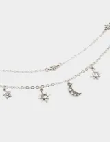 Collar corto de tres hileras con cadena de eslabones plateada. La hilera superior tiene pequeños dijes de estrellas, la hilera del medio es una cadena simple y la hilera inferior tiene dijes colgantes de estrellas y una luna creciente.