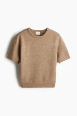 Buzo color beige de punto fino suave con cuello redondo y mangas cortas.