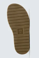 Sandalia tipo cangrejera color beige, con tiras de cuero serraje y hebilla lateral ajustable.