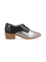 Zapato acordonado de cuero color plateado con puntera fina y detalle de cuero marrón en el talón.