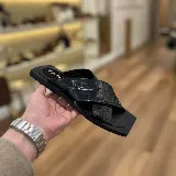 Sandalias negras con tiras anchas cruzadas de cuero con textura tipo cocodrilo y suela plana cuadrada.