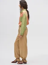 Mono largo de jean celeste con corte holgado, cintura elastizada con cordón ajustable, sin mangas, cuello camisero y cierre frontal con botones. Presenta bordados de motivos playeros en el pecho.