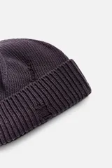 Gorro de lana tejido en punto morado oscuro, con vuelta y detalles rotos.