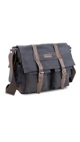 Morral de tela canvas color gris con detalles en cuero marrón. Tiene tapa con hebillas, doble bolsillo frontal, trasero y laterales. Interior espacioso con compartimento para notebook de 15". Correa de galón regulable.