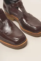 Zapato guillermina de cuero vacuno charol color negro, con suela de goma color marrón.