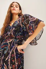 Vestido largo con estampado paisley en tonos azul, negro, rojo y dorado. Tiene escote en V, mangas cortas amplias, elástico en la cintura con lazo y está confeccionado en viscosa con jacquard de lurex.