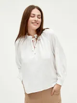 Blusa blanca de mangas largas con cuello fruncido y lazo.