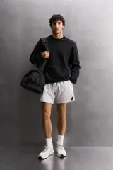Shorts deportivos color verde oliva confeccionados en tejido técnico ligero y elástico. Cuenta con forro interior, cintura elástica ajustable con cordón, bolsillos laterales, bolsillo de seguridad en espalda con cierre de cremallera, bajo con aberturas laterales y logo estampado en la pierna.