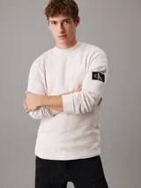 Remera color crema de punto gofrado con cuello redondo, mangas largas, puños de canalé e insignia con el logo de Calvin Klein en la manga.