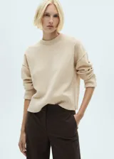 Sweater color beige de tejido de punto con cuello redondo y mangas largas.