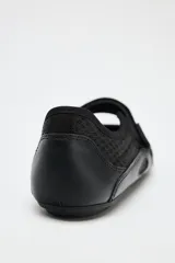 Zapato tipo bailarina color negro, con capellada de cuero sintético y rejilla. Tiene tira con velcro en el empeine y suela plana.