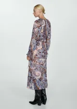 Vestido largo de gasa con estampado paisley en tonos celeste, marrón y rosa. Tiene escote en V con volantes, mangas largas con puños elásticos y lazos, y forro interior.