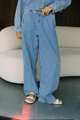 Pantalón de jean celeste, de tiro medio, corte wide leg, estilo jogger con cintura elástica ajustable con cordones, bolsillos delanteros de vivo y bolsillos de plastrón en espalda.