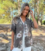 Camisa de algodón color chocolate con estampado floral en tonos beige. Cuenta con cuello camisero, cierre frontal de botones y mangas largas con trabas para arremangar.