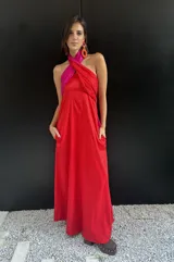Vestido largo strapless con corpiño fruncido en color fucsia brillante y falda amplia en color rojo vibrante. La prenda tiene bolsillos laterales.