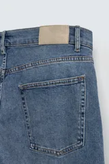 Pantalón de jean negro, corte slim fit, con tiro medio, cinco bolsillos, efecto lavado y cierre frontal con cremallera y botón.