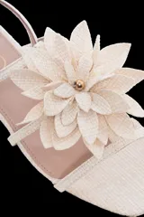 Sandalia plana color dorado con punta cuadrada y tiras finas. Presenta una flor decorativa en el empeine.