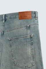 Pantalón de jean celeste de corte amplio con efecto lavado. Tiene cinco bolsillos y costuras frontales en las piernas.