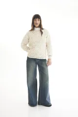 Sweater de punto calado color crema, con cuello alto y mangas largas.
