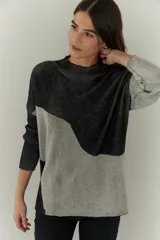 Buzo de punto con diseño geométrico en bloques de color gris y negro, de cuello redondo y mangas largas.