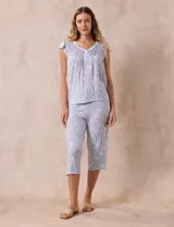 Conjunto de pijama marca René Rofé, compuesto por una remera de escote en V con botones y un pantalón capri con cintura elastizada, ambos en tejido soft estampado con motivos florales en tonos celeste y blanco.