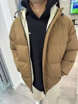 Campera puffer marrón claro con capucha y cierre frontal.