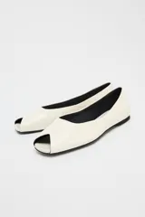 Zapato plano tipo bailarina de piel color crema con efecto craquelado y punta cuadrada abierta.