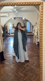 Ruana tejida a mano en color gris, con diseño calado y flecos largos.