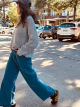 Pantalón de jean ancho de color azul, con bordado de las iniciales AW en el bolsillo trasero.