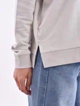 Sweatshirt color gris claro, de corte holgado y mangas largas.