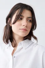 Camisa blanca de manga larga con cuello y puños bordados con calados. Corte clásico y cierre frontal con botones.