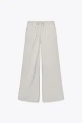 Pantalón palazzo color verde oliva de tejido fluido, tiro medio, cintura elástica ajustable con cordones y bolsillos laterales.