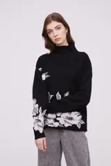 Sweater de tejido suave con estampado floral en tonos beige y blanco, con cuello alto y mangas largas.