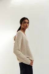 Sweater de punto calado color crudo, con escote en V y mangas largas.