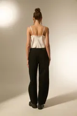 Pantalón de jean negro de corte ancho y tiro bajo, con detalles de tachas metálicas en los bolsillos delanteros y a lo largo de las costuras laterales.