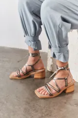 Sandalias plateadas con tiras finas cruzadas y tobilleras con cordones. Tacón de madera.