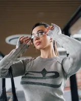 Sweater gris de punto con rayas verticales negras, cuello redondo, mangas largas con detalle de flecos y ruedo con terminación irregular.