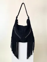 Bolso bandolera negro de cuero con flecos largos, cierre metálico y correa ajustable. Presenta dos bolsillos frontales con cierre. Marca Alhena.