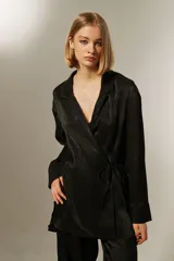 Blusa negra con corte cruzado, escote en V, mangas largas y lazo lateral para ajustar.