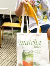 Bolso tote de tela color crudo con asas de algodón. Estampado frontal de un vaso de matcha juice.