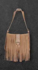 Cartera bandolera de cuero color tostado con flecos largos de gamuza en el frente y correa de hombro ajustable. Cierre con hebilla metálica. Hecha a mano.