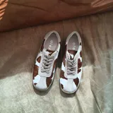 Championes de cuero con estampado de vaca en blanco y marrón, con cordones y suela de goma color beige.